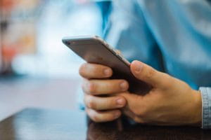 Man's hands holding iPhone in denim shirt