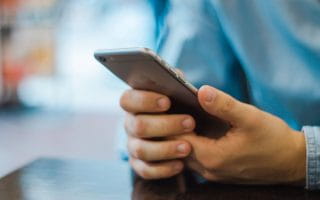 Man's hands holding iPhone in denim shirt