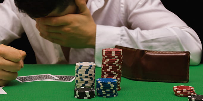 A man covering his face in front of a casino table