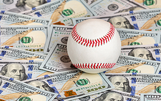 A baseball on top of USD banknotes