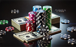 Casino chips stacked next to a pile of money on a black background