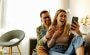 Excited Young Couple Relaxing with Smartphone