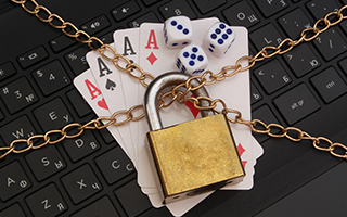 Dice and playing cards lying on a laptop keyboard, locked with a chain.